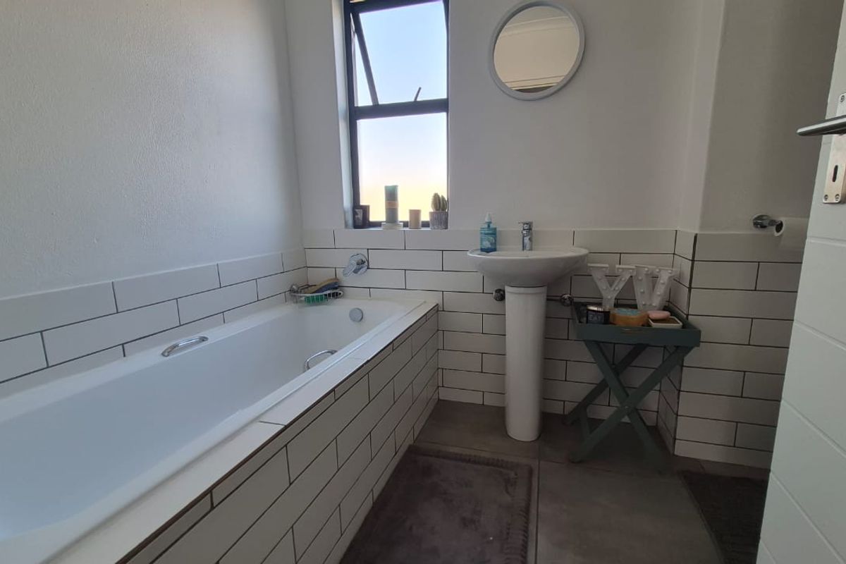 A clean, modern bathroom featuring a built-in bathtub, pedestal basin, and classic white subway wall tiles with dark grout.