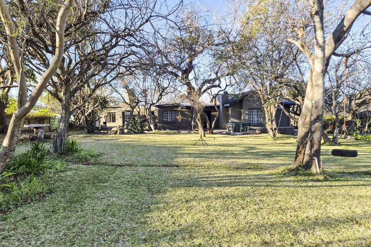 A spacious rear garden featuring mature trees and a view of the back elevation of the house.