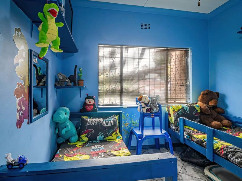 A bedroom featuring tiled flooring, built-in shelving, and a window fitted with security bars.