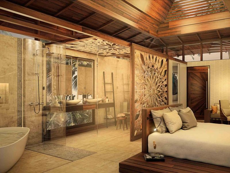 Luxurious open-plan bedroom suite featuring a vaulted timber ceiling, integrated ensuite bathroom with a freestanding bathtub, walk-in shower, and intricate decorative timber partitioning.