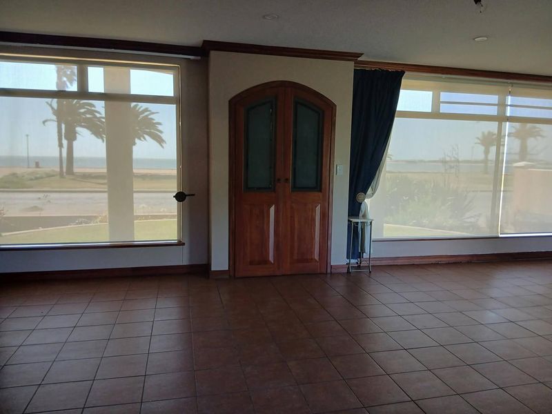 Spacious living area featuring large windows with scenic views, tiled flooring, and elegant arched double doors, offering a bright and open atmosphere.