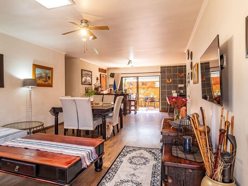 Spacious open-plan living and dining area featuring laminate flooring, a ceiling fan, and sliding glass doors leading to an outdoor patio space.