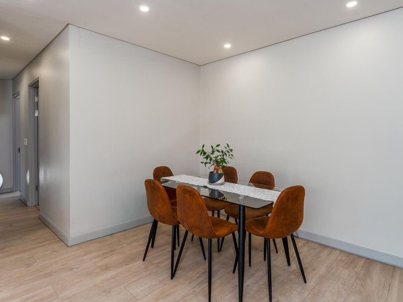 A bright dining area featuring modern laminate flooring and recessed ceiling lighting, providing a clean and neutral space for meals.