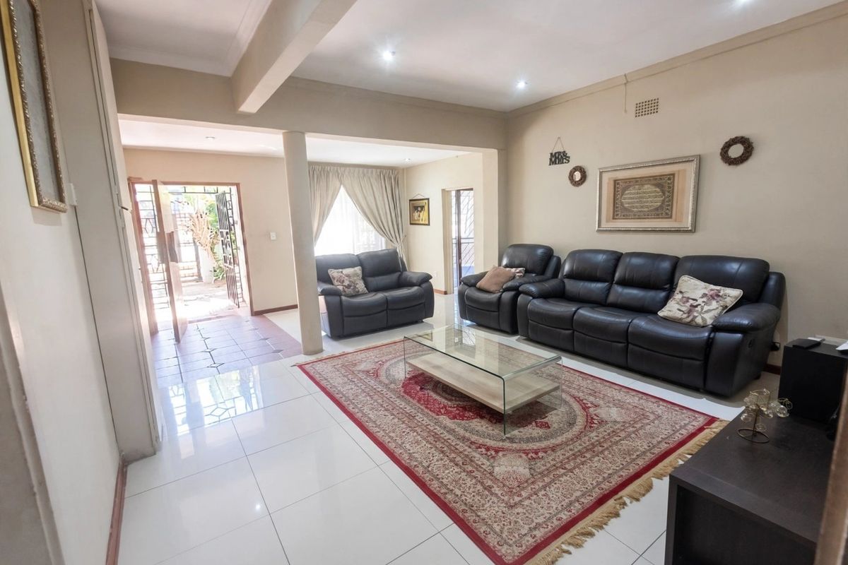 Spacious living room featuring polished white floor tiles, recessed downlighting, and a structural support column, with direct access to an outdoor patio area.