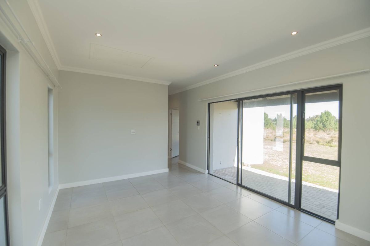 A bright, neutral-toned living area featuring large sliding glass doors that provide seamless access to the outdoor patio and garden.