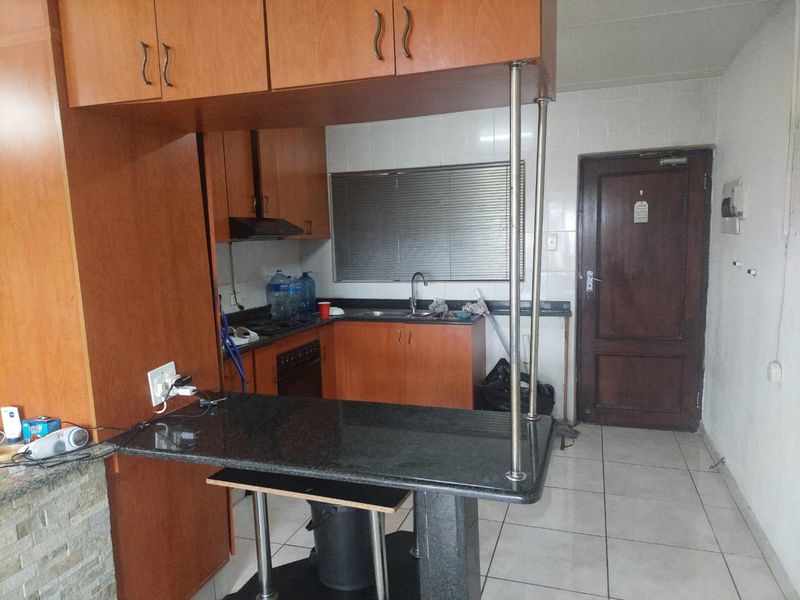 A functional kitchen featuring wood-finish cabinetry, granite countertops, a breakfast bar, and tiled flooring, offering a practical layout for daily use.