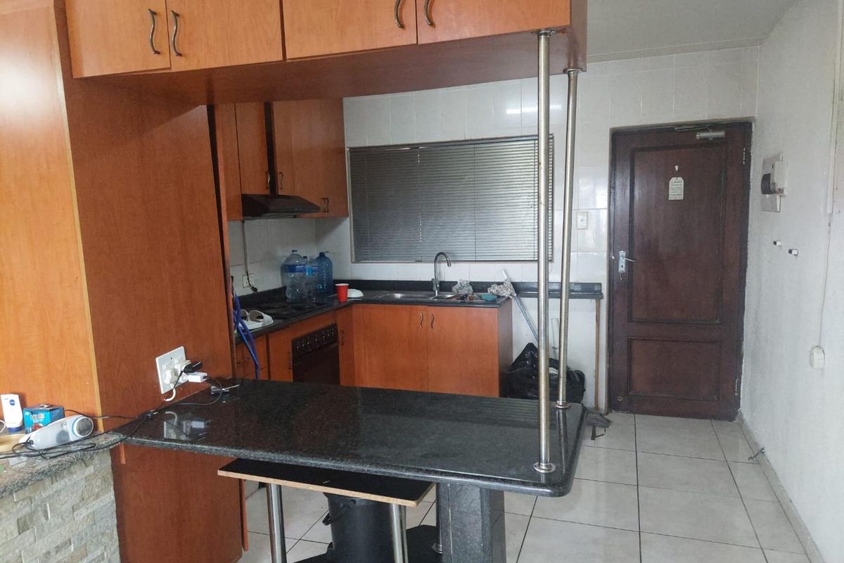 A functional kitchen featuring wood-finish cabinetry, granite countertops, a breakfast bar, and tiled flooring, offering a practical layout for daily use.