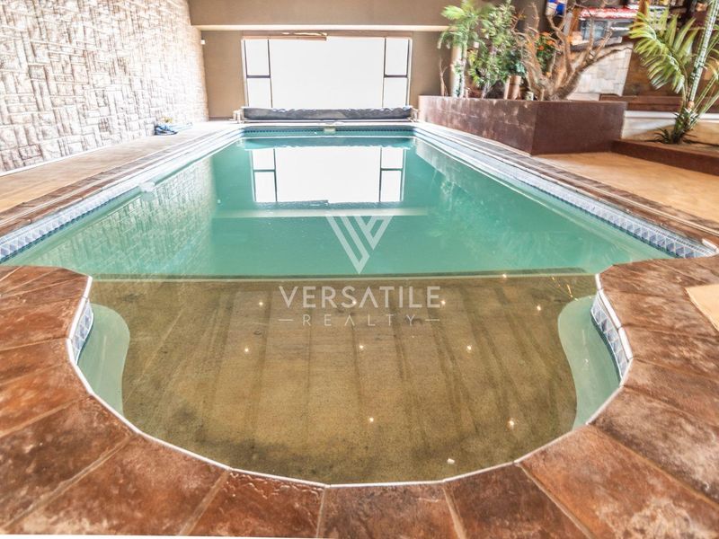 An indoor swimming pool area featuring stone-clad walls, tiled coping, and a built-in planter box, creating a unique recreational space.