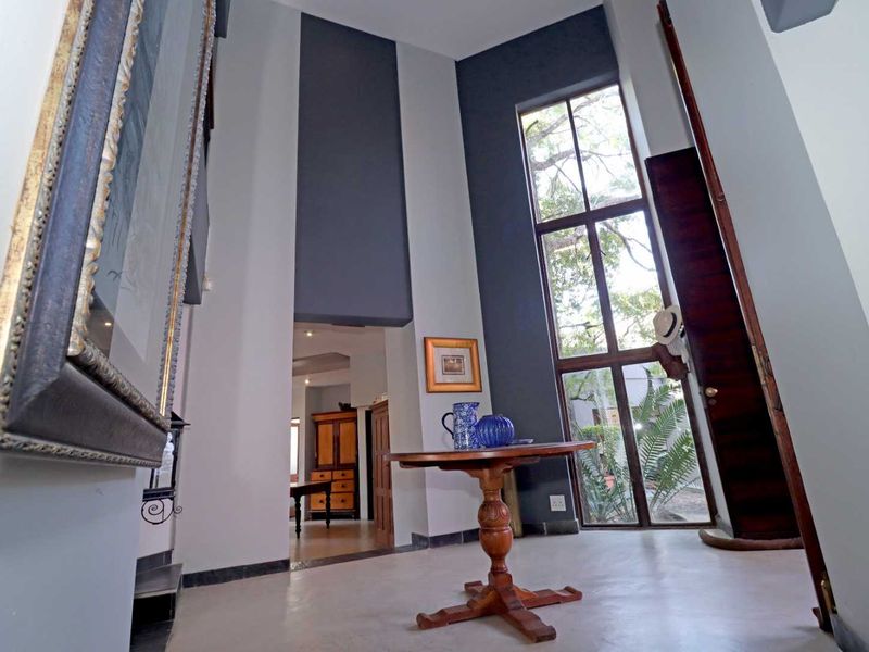 Spacious double-volume entrance hall featuring high ceilings, large windows providing natural light, and neutral tiled flooring.