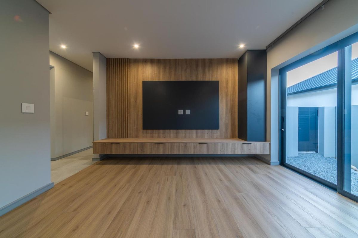 Modern living room featuring custom timber cabinetry, slat wall detailing, recessed lighting, and large sliding glass doors opening to an outdoor area.