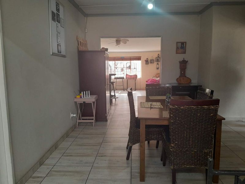 Open plan living and dining area featuring tiled flooring and a ceiling fan, connecting to an adjacent room.