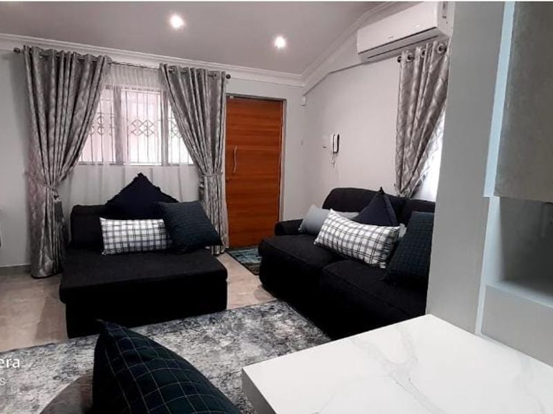 A well-maintained living room featuring tiled floors, recessed lighting, and a wall-mounted air conditioning unit.