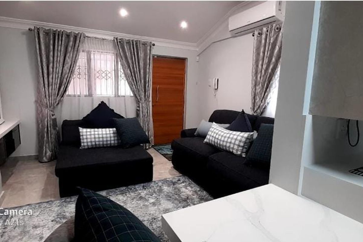 A well-maintained living room featuring tiled floors, recessed lighting, and a wall-mounted air conditioning unit.