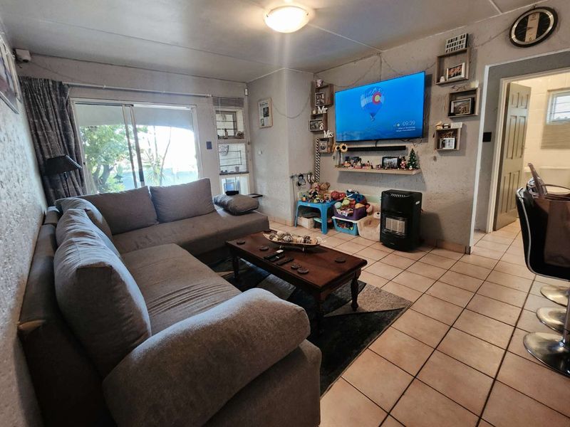 Living room featuring tiled flooring and a sliding glass door leading to an outdoor area, with access to an adjacent bathroom.