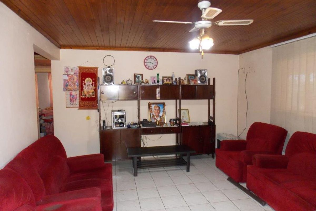 A living room featuring a timber tongue and groove ceiling, ceiling fan, and ceramic tiled flooring.