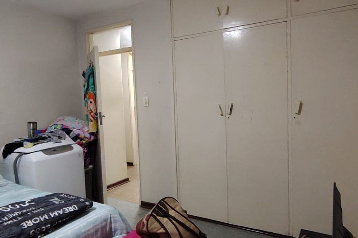 A bedroom featuring built-in cupboards with white doors and access to an adjoining hallway.