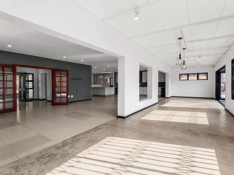 Spacious open-plan living area featuring a mix of tiled and polished concrete floors, recessed lighting, and direct access through classic french doors.