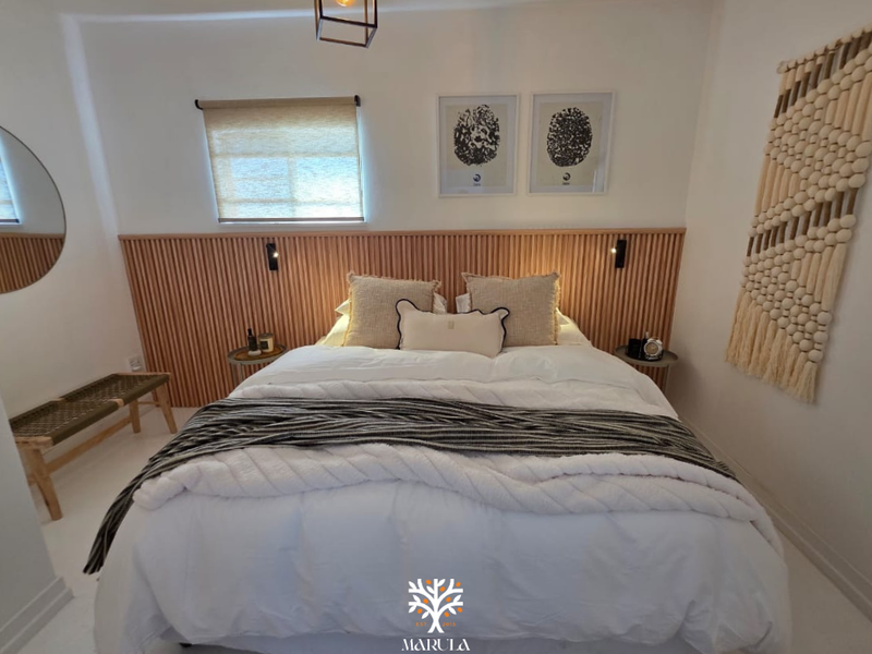 A well-presented bedroom featuring a modern timber slat feature wall, neutral decor, and integrated lighting.
