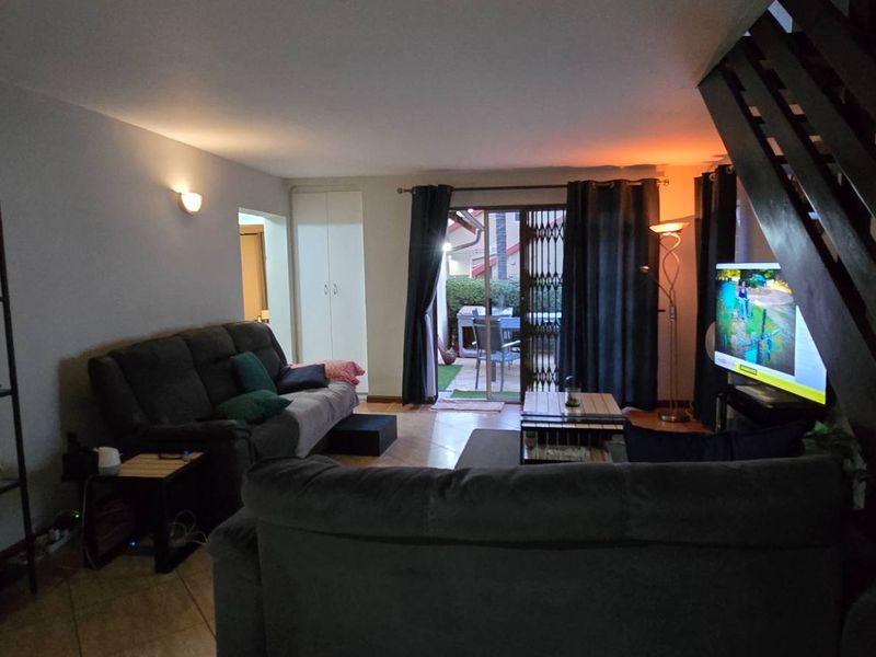 Spacious living room featuring tiled flooring, a staircase, and sliding glass doors providing access to the outdoor patio area.