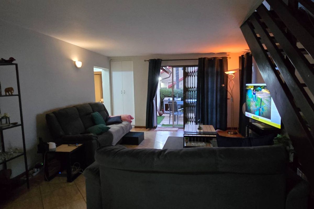 Spacious living room featuring tiled flooring, a staircase, and sliding glass doors providing access to the outdoor patio area.