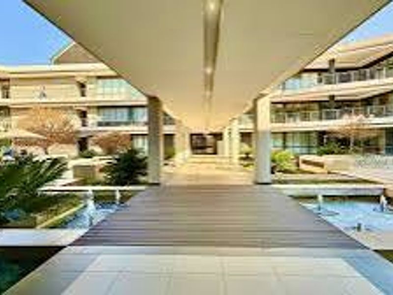 A modern office complex featuring a central covered walkway, landscaped gardens, and integrated water features between multi-story building wings.