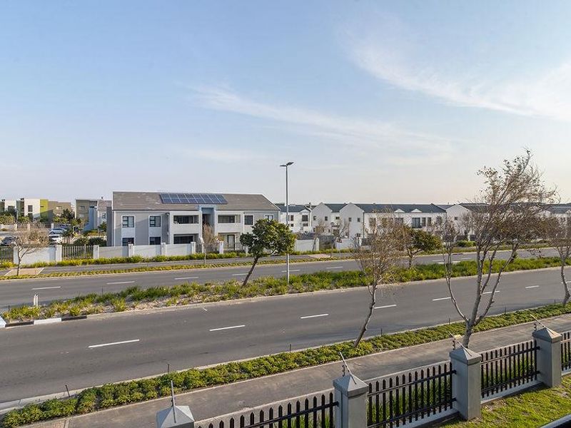 An elevated view overlooking a suburban street, surrounding residential apartment complexes, and local infrastructure under a clear sky.