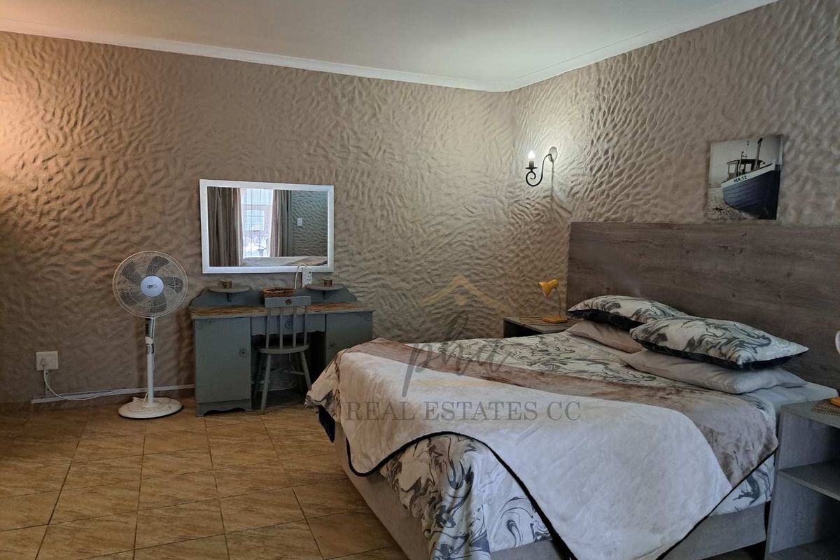 A bedroom featuring tiled flooring and a textured feature wall with wall-mounted lighting.