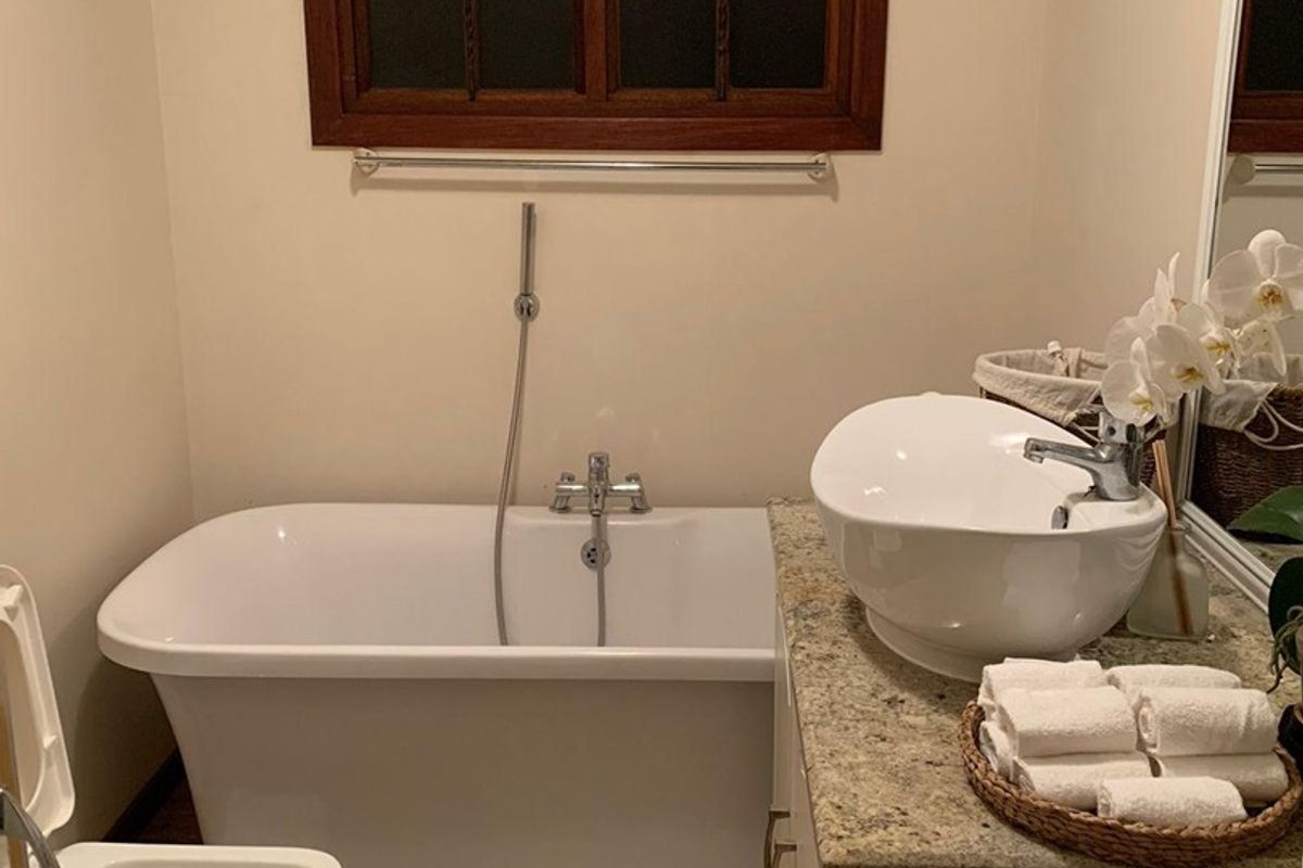 A well-maintained bathroom featuring a freestanding bathtub, vessel sink on a granite vanity, and a timber-framed window.