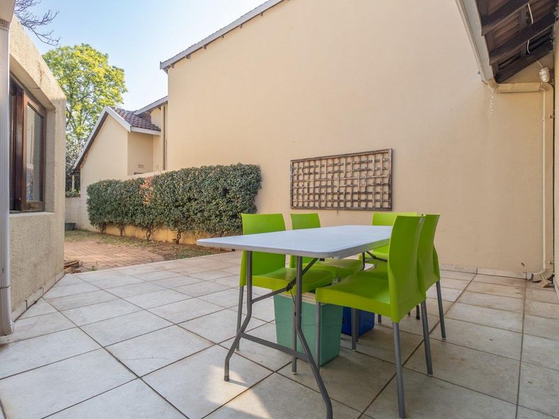 A paved outdoor patio area featuring tiled flooring and direct access to the home via a sliding door, suitable for outdoor dining.