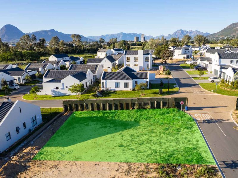 An aerial view of a vacant residential plot situated within a modern, established housing estate with mountain views.