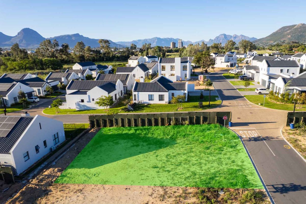 An aerial view of a vacant residential plot situated within a modern, established housing estate with mountain views.