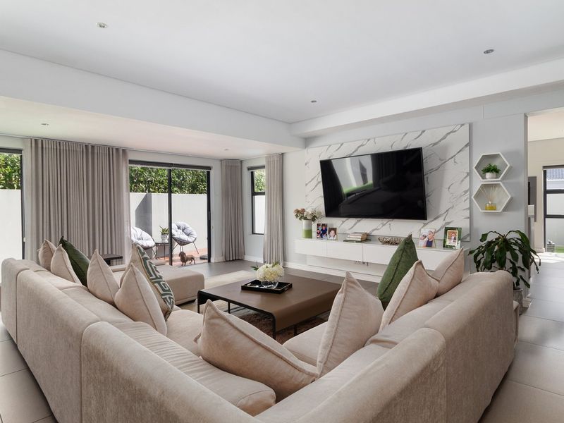 Modern living room featuring a marble-look feature wall, floating media console, recessed lighting, and large sliding glass doors leading to an outdoor patio area.