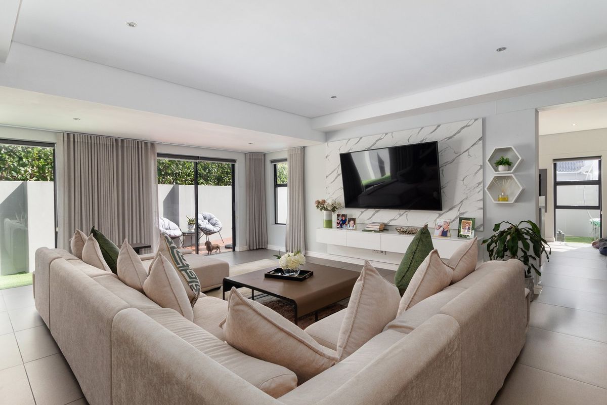 Modern living room featuring a marble-look feature wall, floating media console, recessed lighting, and large sliding glass doors leading to an outdoor patio area.