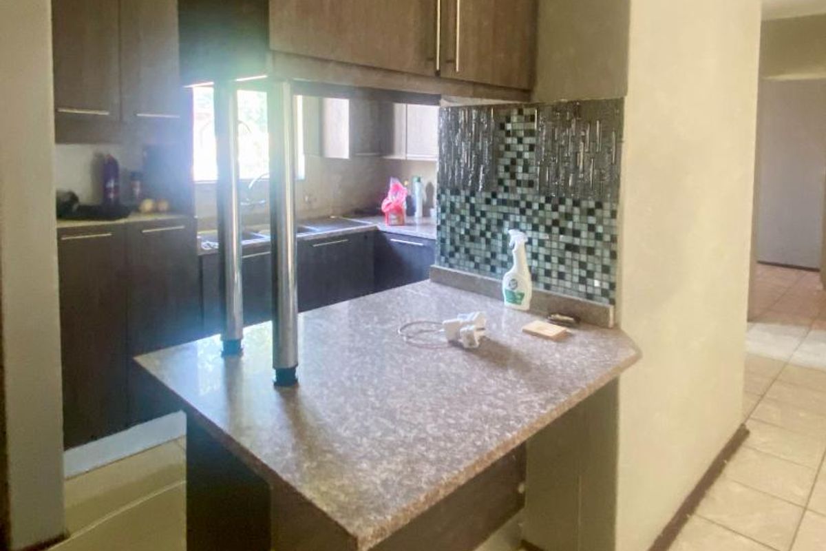 A functional kitchen featuring dark wood cabinetry, a breakfast bar with a laminate countertop, and a decorative mosaic tile backsplash.