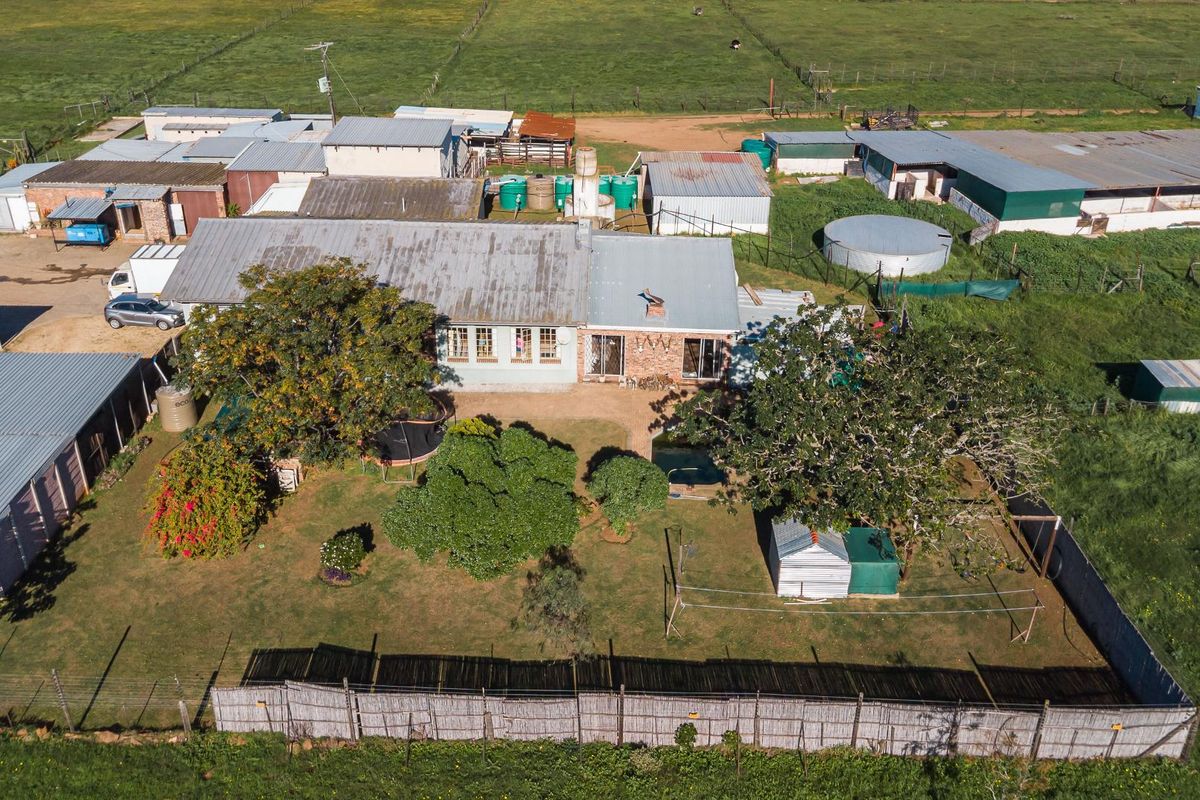 Aerial view of a farm property featuring the main residence, multiple outbuildings, water storage tanks, and surrounding agricultural land.
