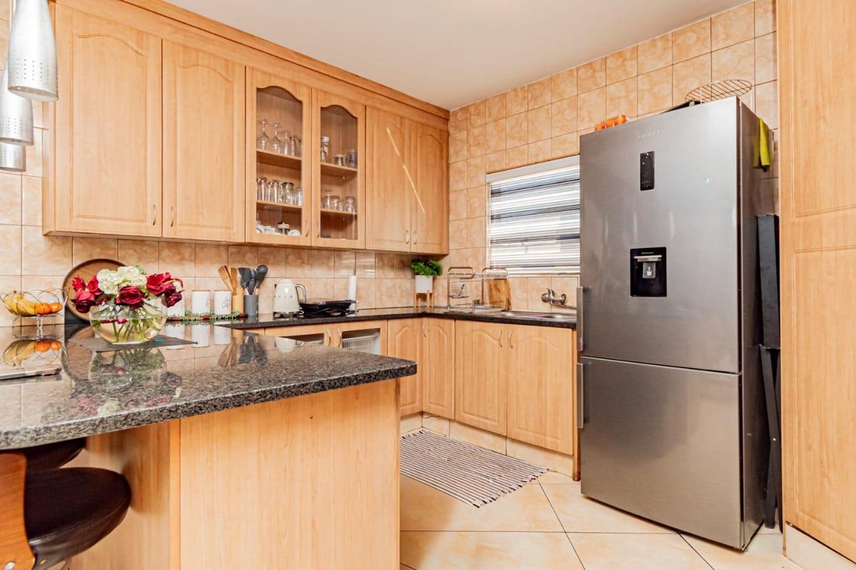 A functional kitchen featuring light wood cabinetry, granite countertops, tiled backsplash, and a double sink, offering a classic and practical layout.