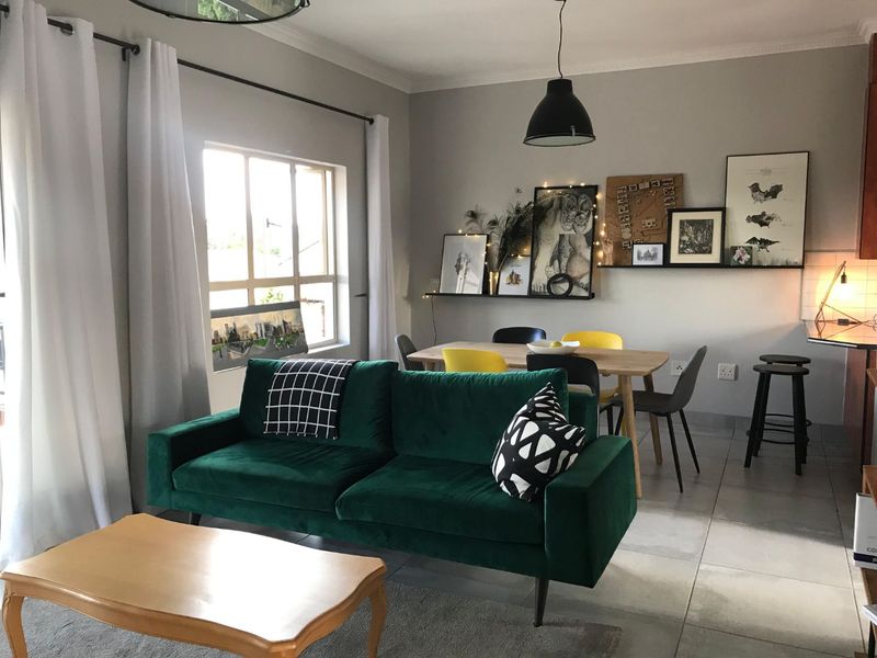 An open-plan living and dining area featuring tiled flooring, neutral walls, and ample natural light from a large window.