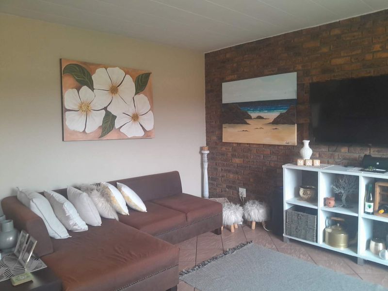 A cozy living room featuring an exposed brick accent wall and tiled flooring, providing a warm and inviting atmosphere.