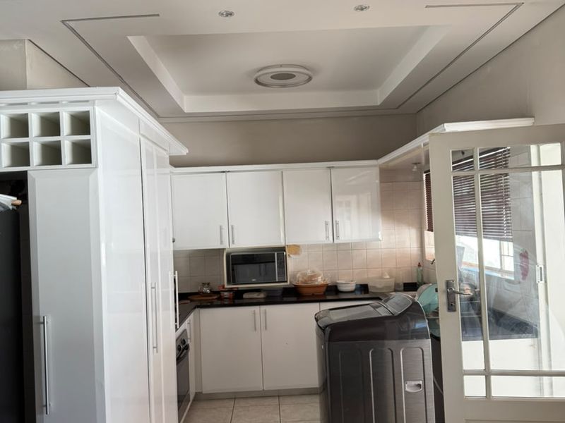 A functional kitchen featuring white cabinetry, granite countertops, built-in microwave, and a decorative tray ceiling with recessed lighting.