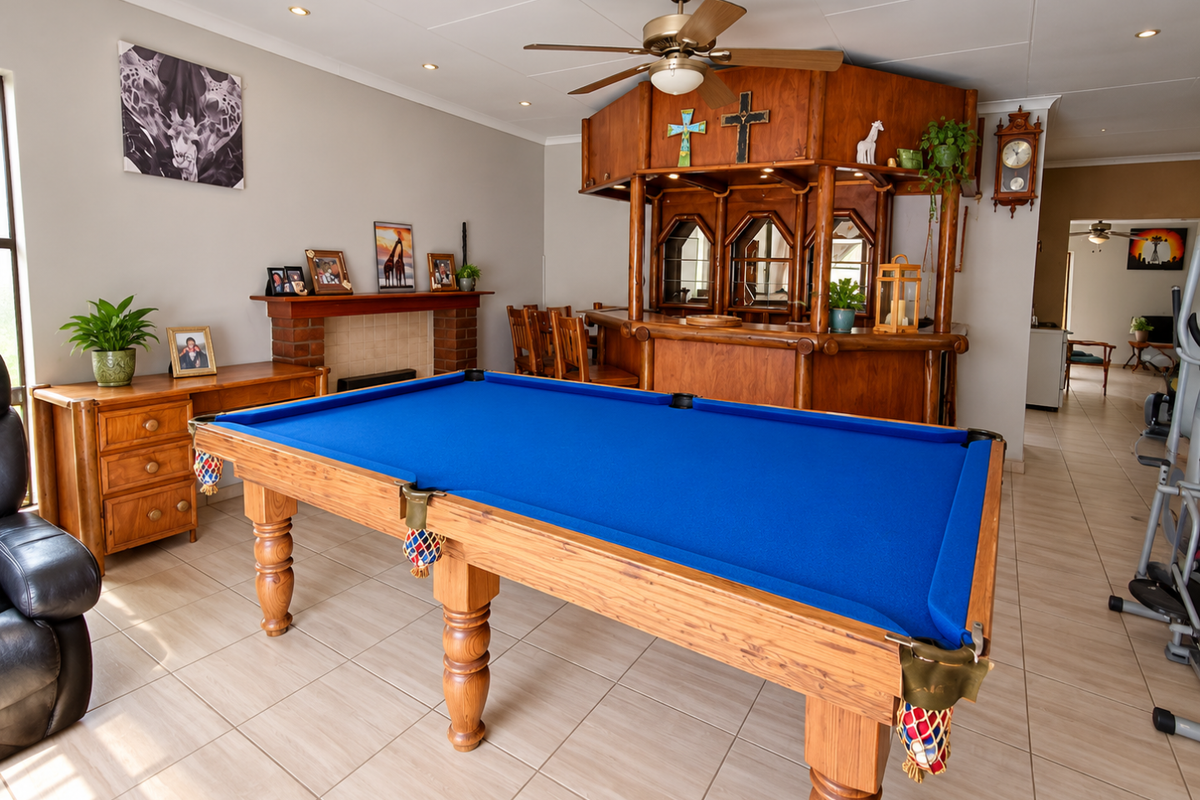 Spacious living area featuring a built-in wooden bar, brick fireplace, ceiling fan, and neutral tiled flooring, offering a versatile entertainment space.