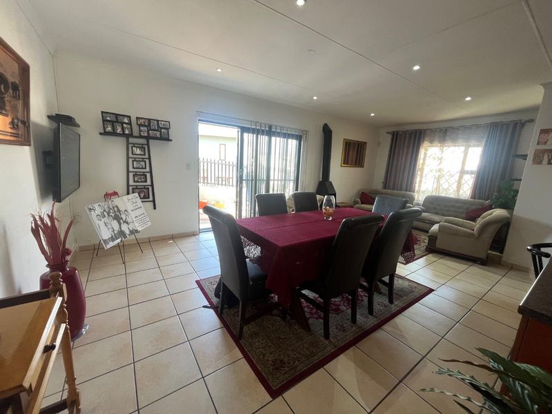Spacious open-plan living and dining area featuring tiled floors, recessed lighting, and a freestanding fireplace with direct access to the outdoor patio.