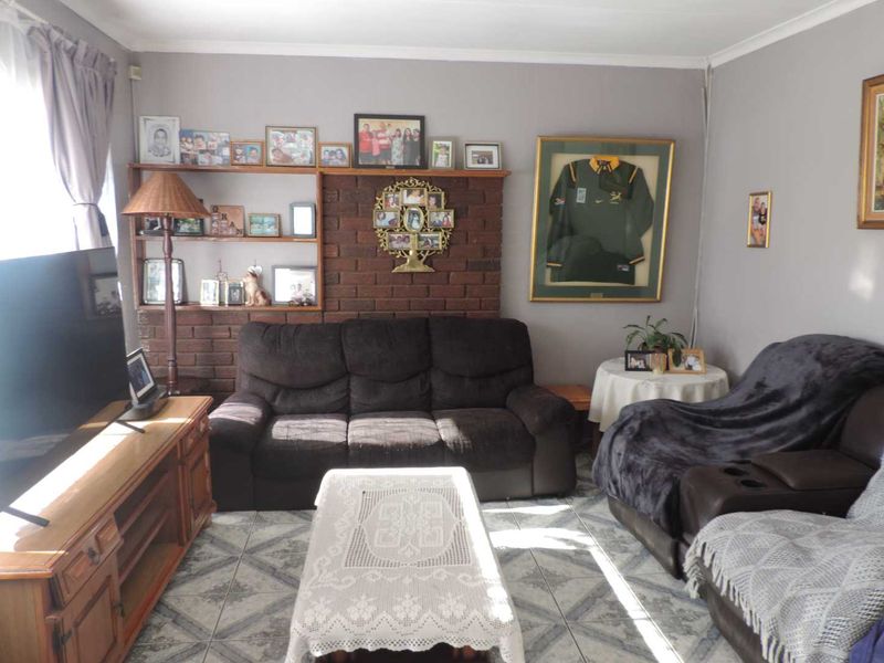 A comfortable living room featuring a brick accent wall with built-in shelving and tiled flooring, offering a cozy and functional space.