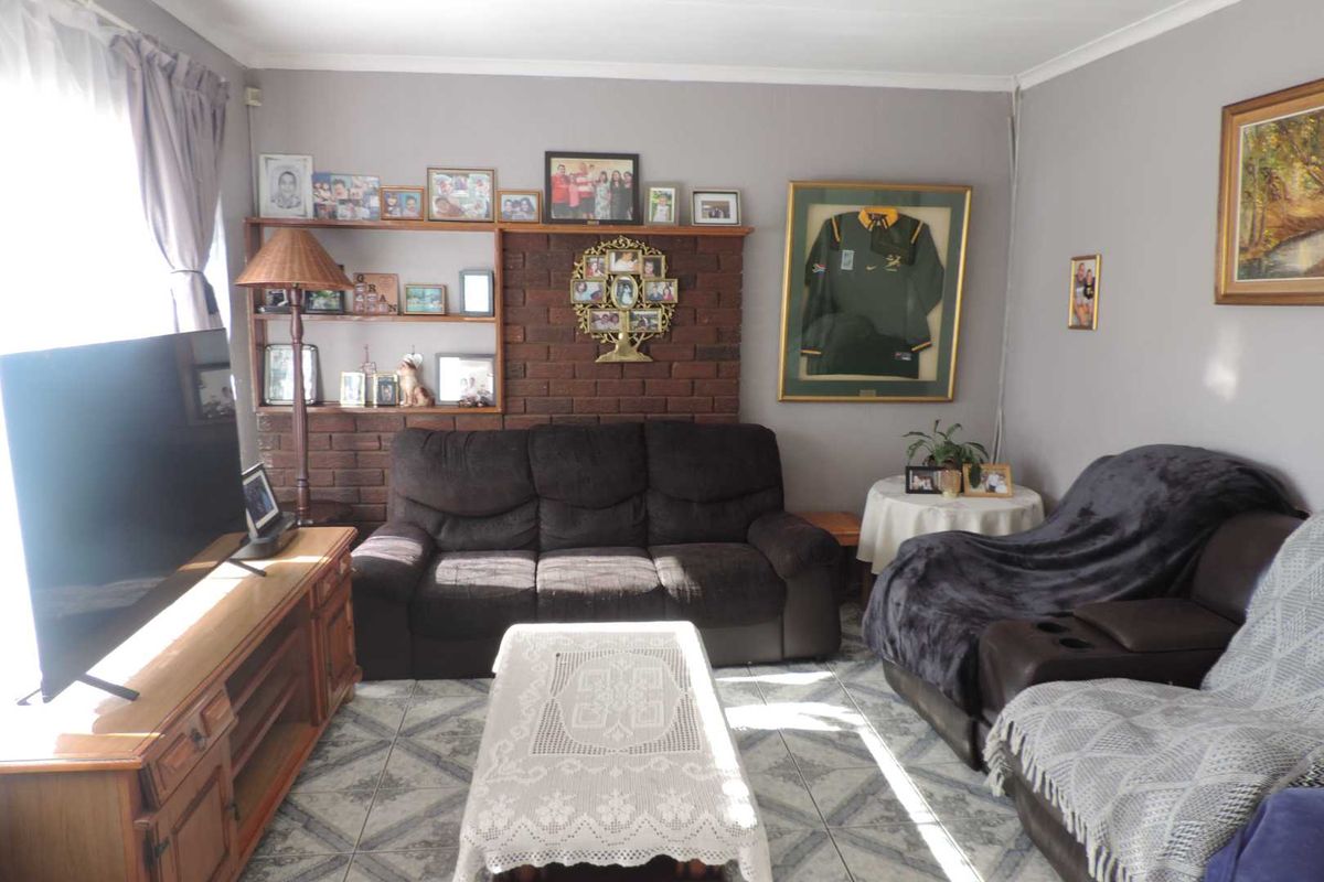 A comfortable living room featuring a brick accent wall with built-in shelving and tiled flooring, offering a cozy and functional space.