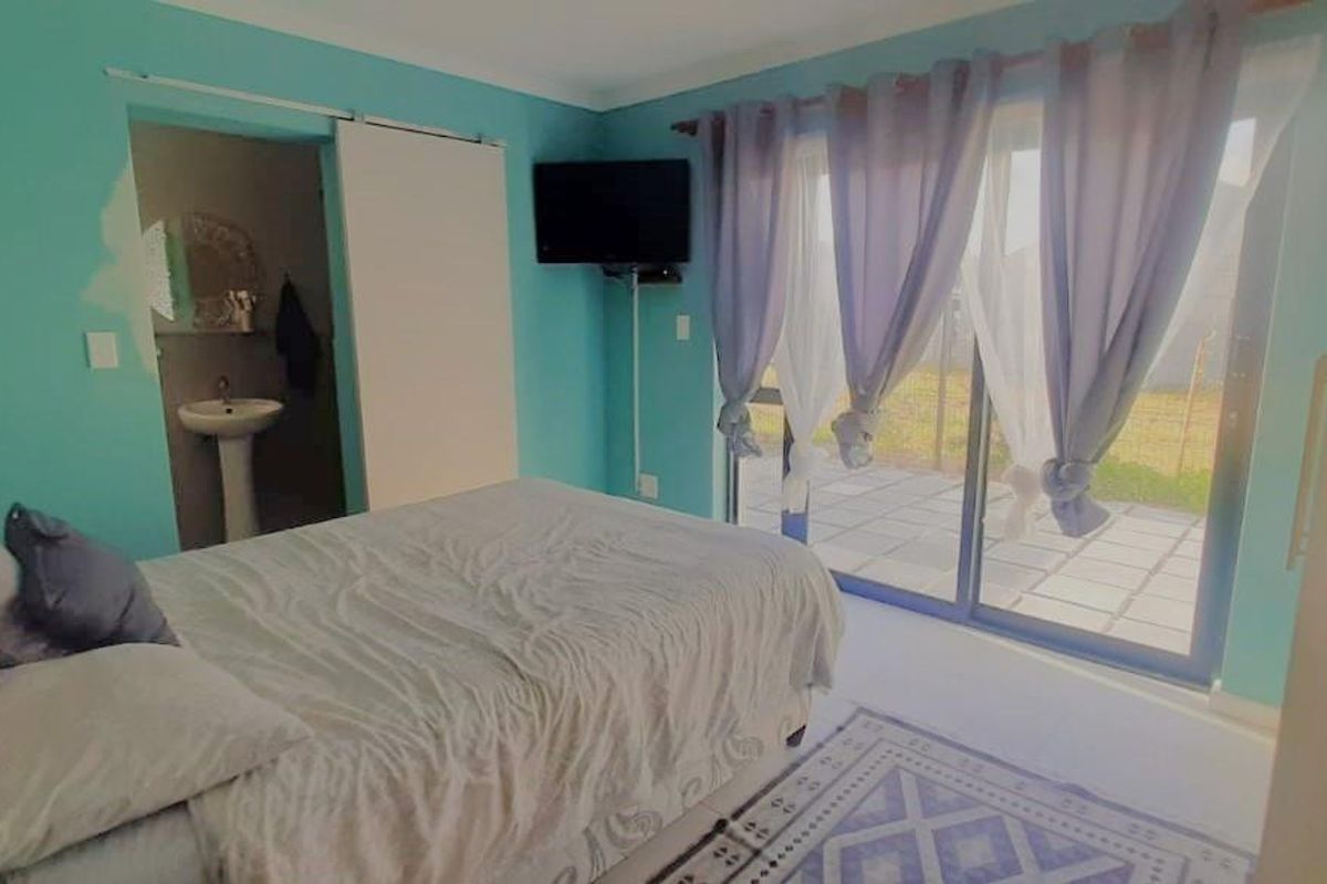 Bedroom featuring sliding glass doors leading to an outdoor patio area and an en-suite bathroom with a pedestal sink.