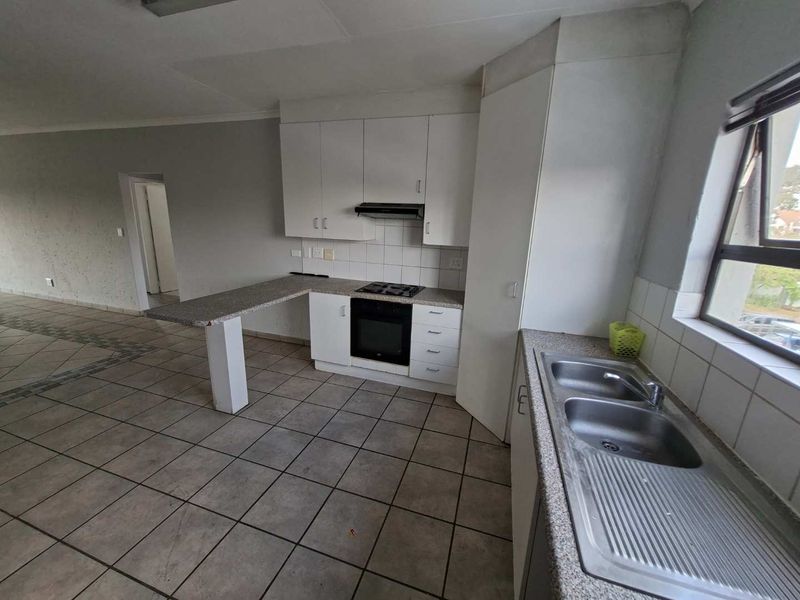 A functional kitchen featuring white cabinetry, laminate countertops, a built-in oven with gas hob, and a double stainless steel sink.