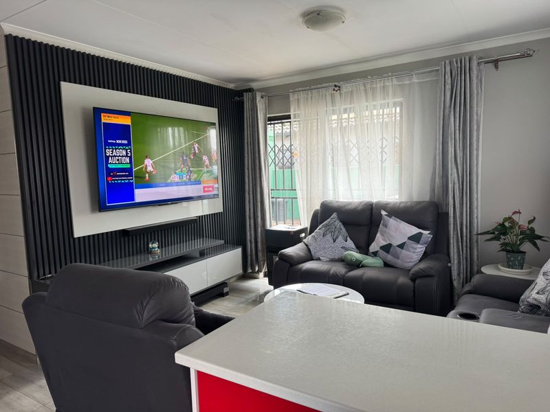 A modern living room featuring a contemporary slatted feature wall with a mounted television and secure window access.