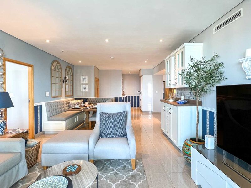 An open-plan living and dining area featuring built-in cabinetry, recessed ceiling lighting, and tiled flooring, creating a cohesive and functional living space.