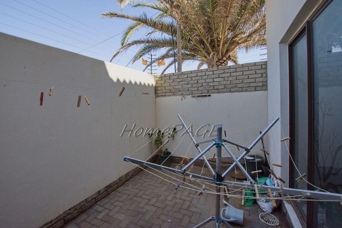 A private rear courtyard featuring paved flooring and high boundary walls, providing a functional outdoor space for laundry or utility use.