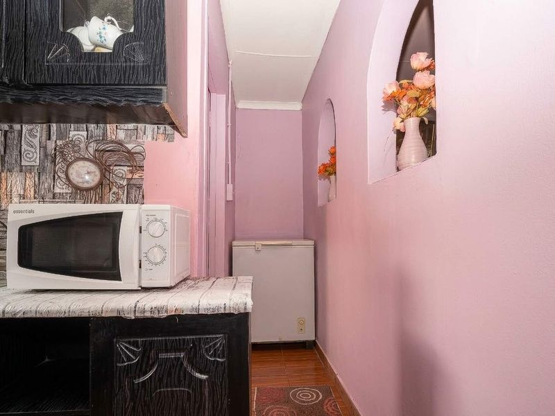A compact scullery or utility area featuring built-in cabinetry, tiled splashbacks, and unique arched wall niches for additional storage or display.