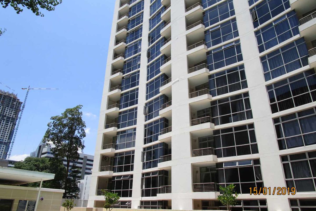 A view of the rear facade of a multi-story apartment building featuring glass windows and private balconies.